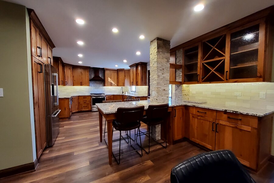 After: warm knotty alder kitchen with stone column and hardwood floors