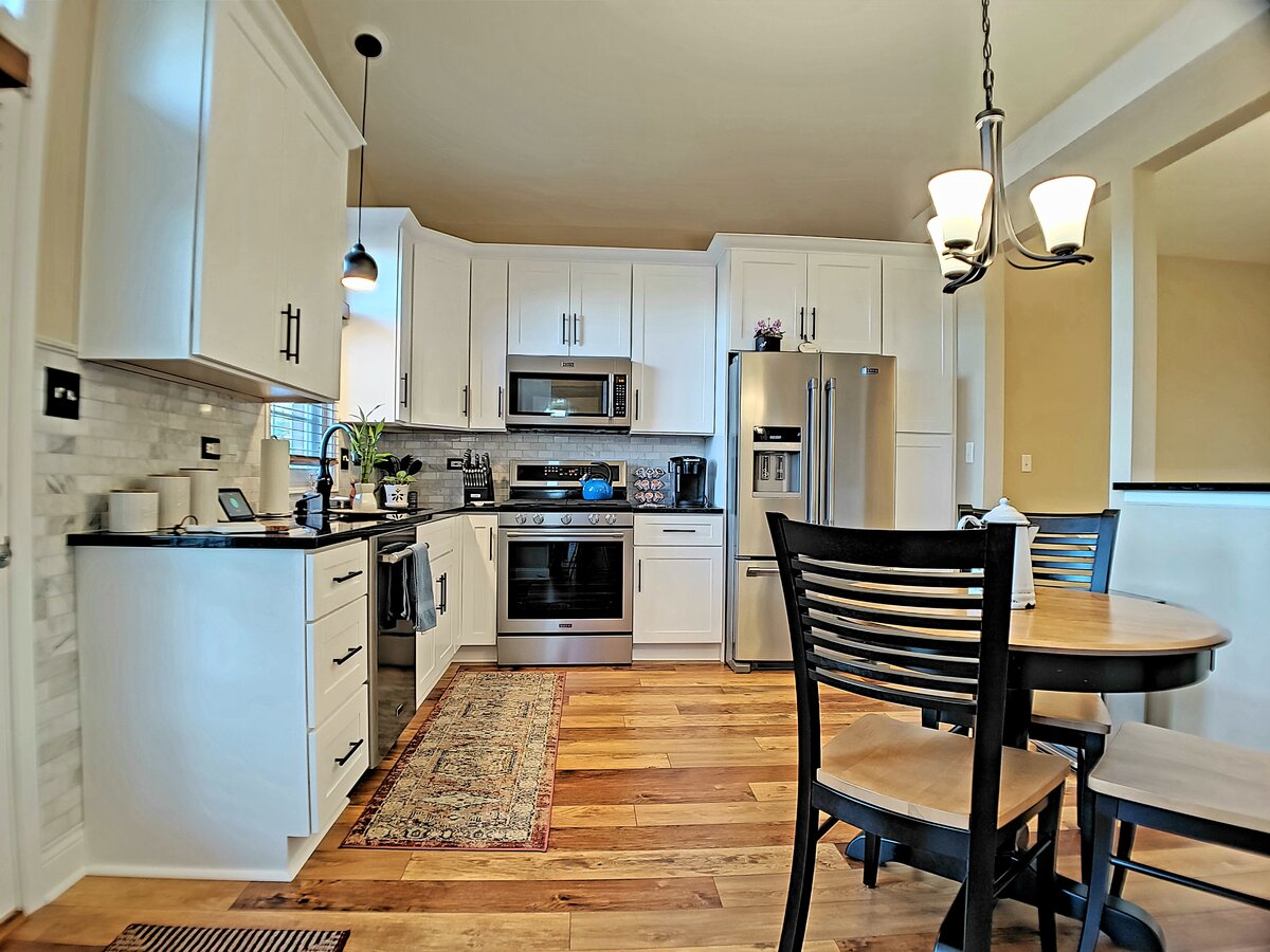 Bright white shaker kitchen remodel with hardwood floors and dining nook by Alpha Development Group
